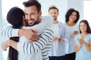 man hugging woman showing appreciation with friends in background