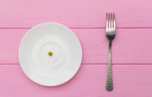 a single pea on plate with fork on the side is an extreme diet